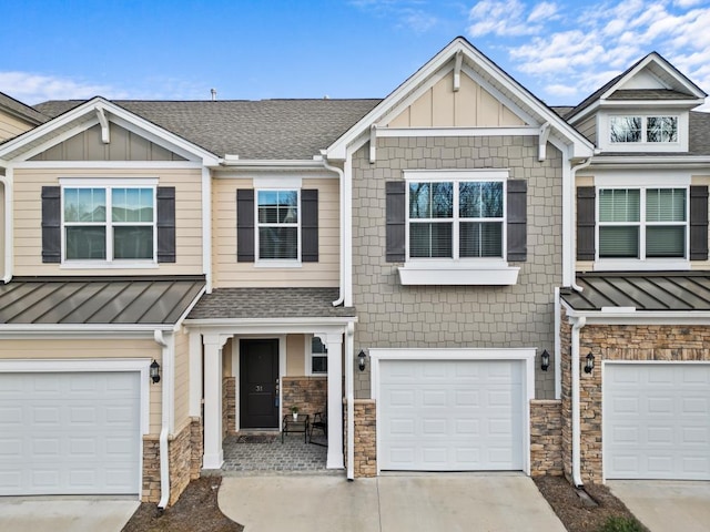 view of front of home featuring stone siding, driveway, a standing seam roof, and board and batten siding