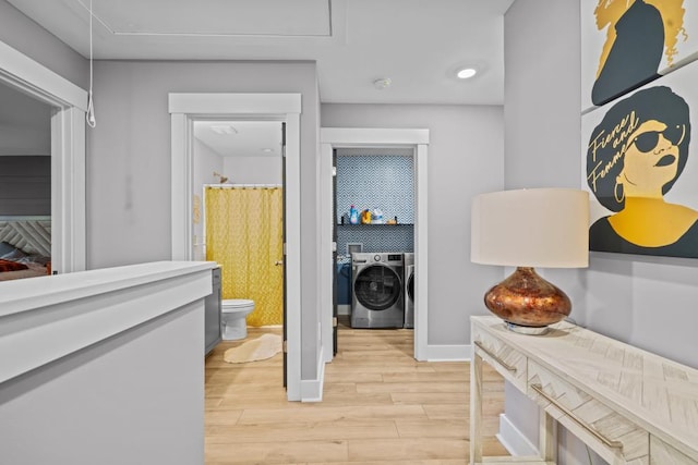 hallway featuring washer and dryer, baseboards, and light wood-style flooring