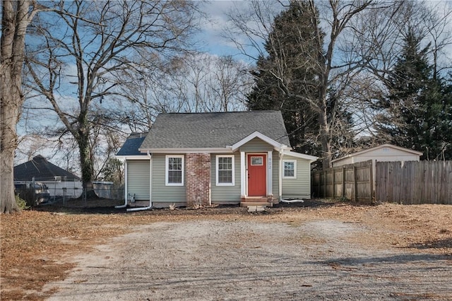 view of front of house featuring a shingled roof, entry steps, fence, and driveway