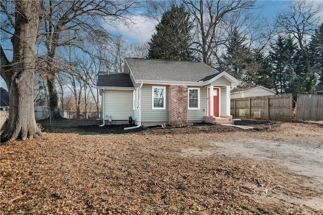 view of front of home with entry steps, roof with shingles, and fence