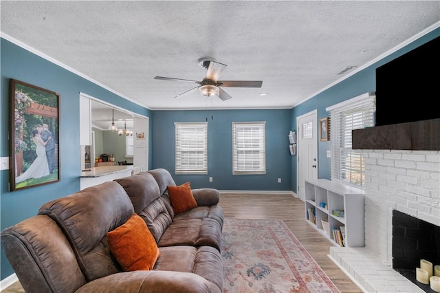 living room featuring a wealth of natural light, a fireplace, crown molding, and wood finished floors