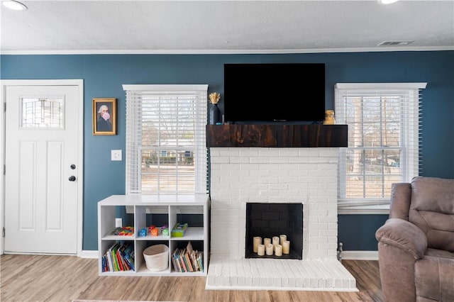 living area featuring a textured ceiling, ornamental molding, wood finished floors, and visible vents