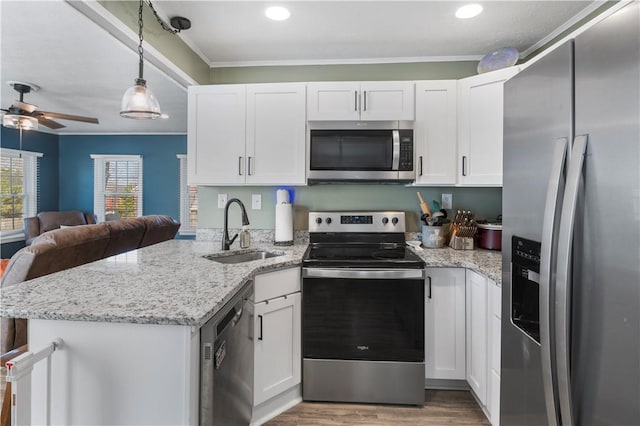 kitchen with stainless steel appliances, open floor plan, white cabinetry, a sink, and a peninsula