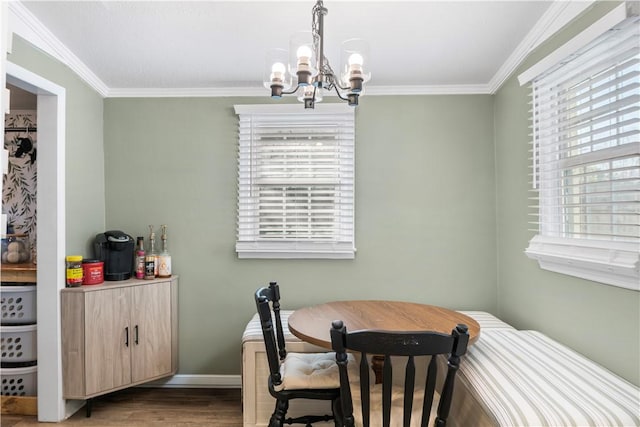 dining room with ornamental molding, plenty of natural light, wood finished floors, and an inviting chandelier