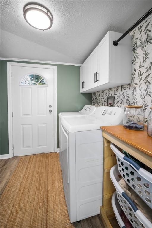 laundry room featuring cabinet space, a textured ceiling, light wood-style floors, and independent washer and dryer