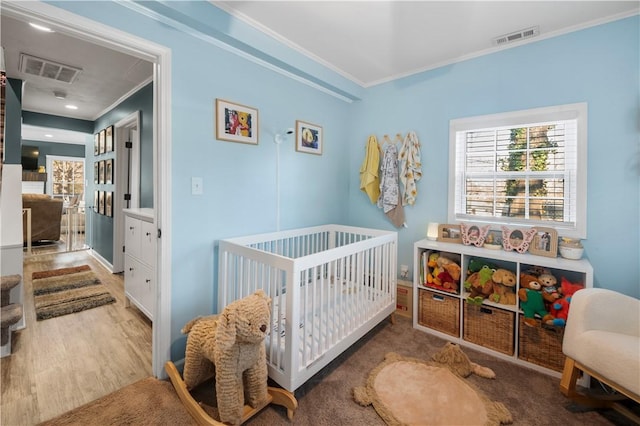 bedroom with visible vents, wood finished floors, and ornamental molding