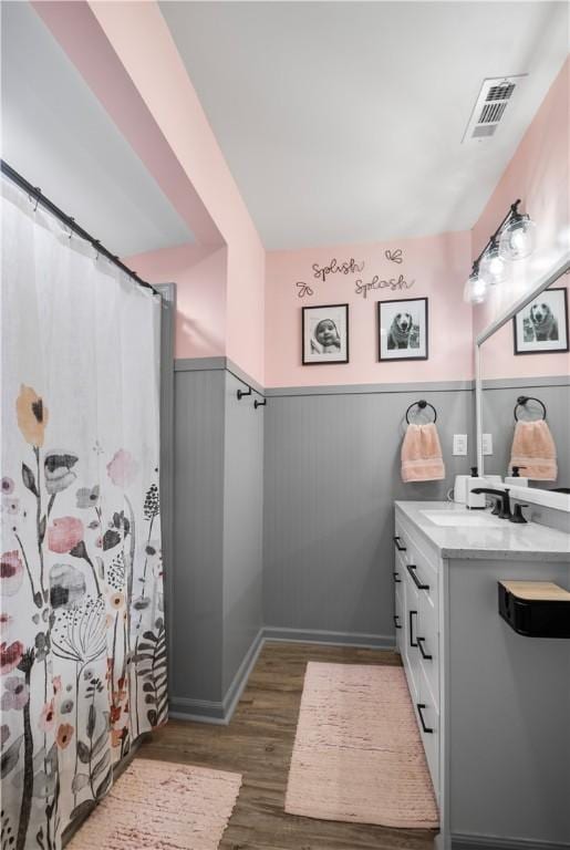 full bath featuring wainscoting, visible vents, vanity, and wood finished floors