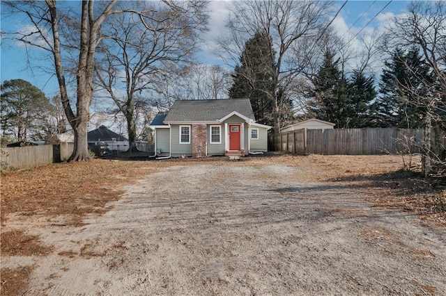 view of front of property with entry steps, driveway, and fence