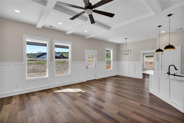 unfurnished living room with dark wood-type flooring, beamed ceiling, a sink, and visible vents