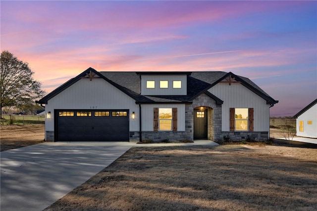 modern inspired farmhouse featuring an attached garage, stone siding, concrete driveway, and roof with shingles