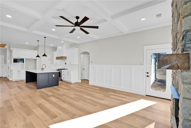 kitchen featuring arched walkways, visible vents, open floor plan, appliances with stainless steel finishes, and wall chimney exhaust hood