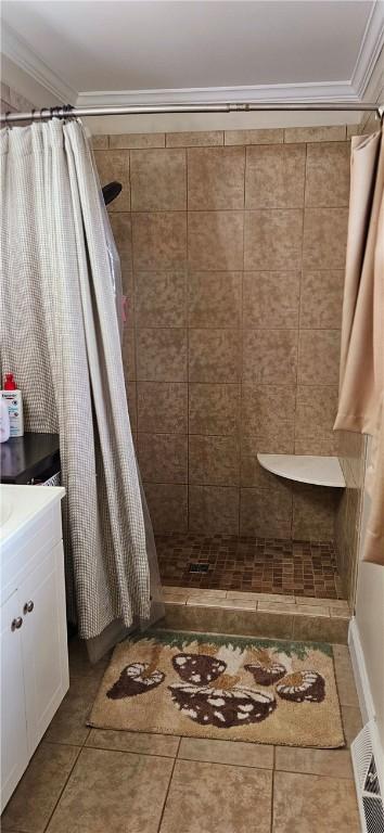 full bathroom featuring a stall shower, tile patterned flooring, crown molding, and vanity