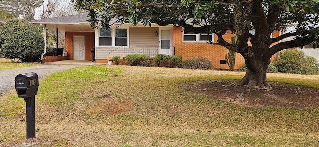 view of front of home featuring driveway, brick siding, an attached carport, covered porch, and a front yard