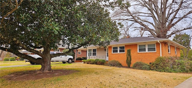 view of front of home featuring crawl space, brick siding, a chimney, and a front lawn