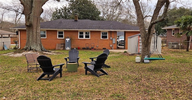 back of property featuring a lawn, an outbuilding, fence, a storage unit, and brick siding