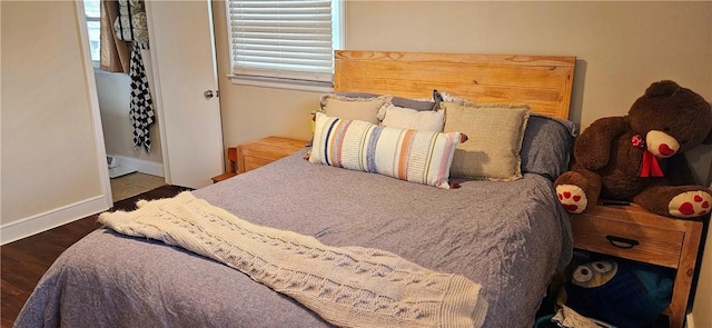 bedroom with multiple windows, baseboards, and wood finished floors