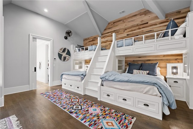 bedroom featuring vaulted ceiling with beams, wood walls, visible vents, baseboards, and dark wood-style floors