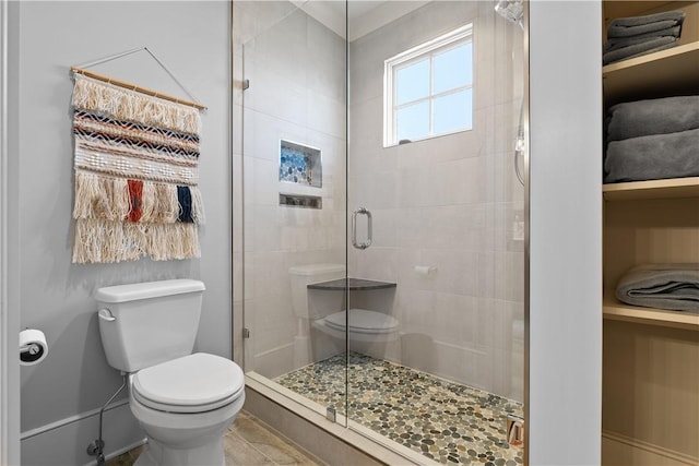 bathroom with a shower stall, toilet, and baseboards