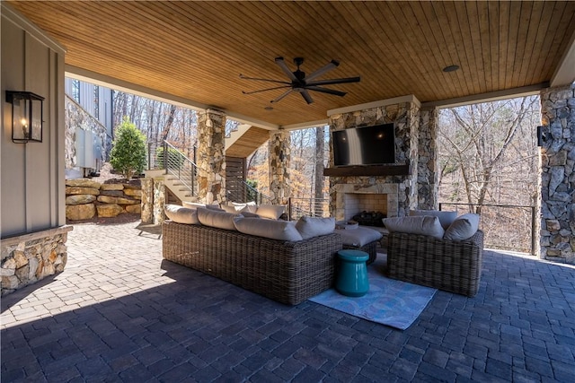 view of patio with an outdoor living space with a fireplace, stairway, and a ceiling fan