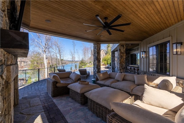 view of patio with a water view, a balcony, ceiling fan, and an outdoor living space