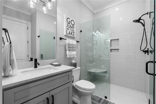 bathroom featuring a stall shower, vanity, toilet, and crown molding