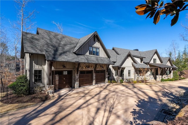 view of front of property with board and batten siding, stone siding, driveway, and a shingled roof