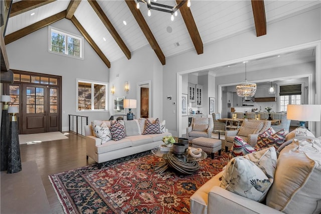 living area with high vaulted ceiling, a healthy amount of sunlight, wood finished floors, and an inviting chandelier