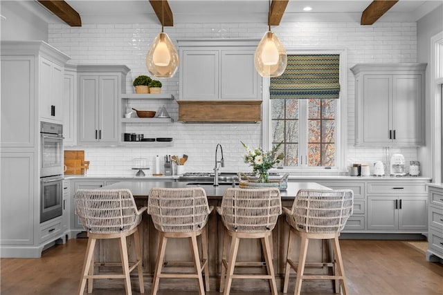 kitchen featuring dark wood-style floors, decorative backsplash, stainless steel double oven, and beamed ceiling