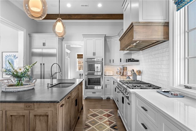 kitchen featuring custom range hood, visible vents, backsplash, appliances with stainless steel finishes, and a sink