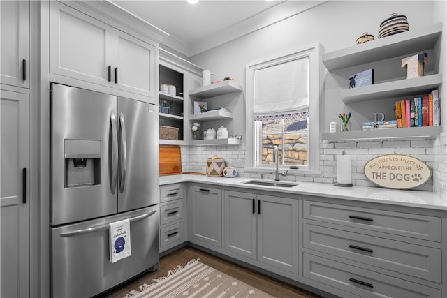 kitchen with a sink, open shelves, gray cabinets, and stainless steel fridge