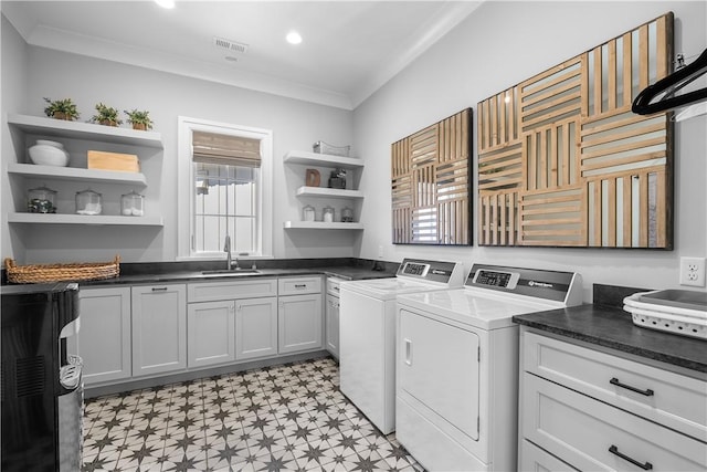 washroom with cabinet space, visible vents, washing machine and clothes dryer, crown molding, and a sink