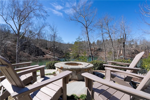 exterior space featuring a fire pit, a water view, and a wooded view