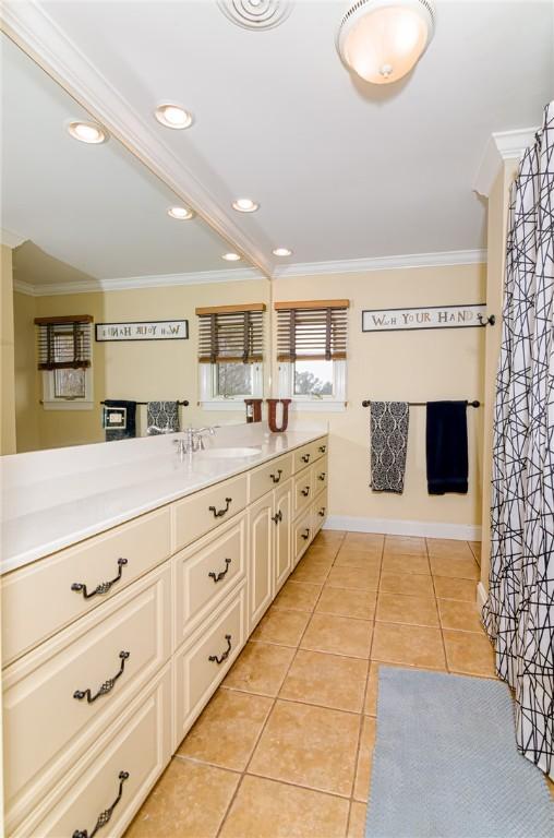 bathroom featuring baseboards, vanity, ornamental molding, and tile patterned floors