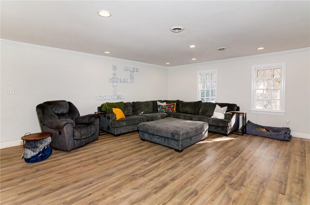 living area featuring visible vents, baseboards, ornamental molding, light wood-style floors, and recessed lighting