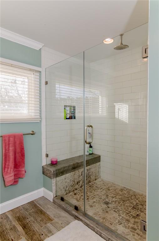 bathroom featuring ornamental molding, a shower stall, baseboards, and wood finished floors