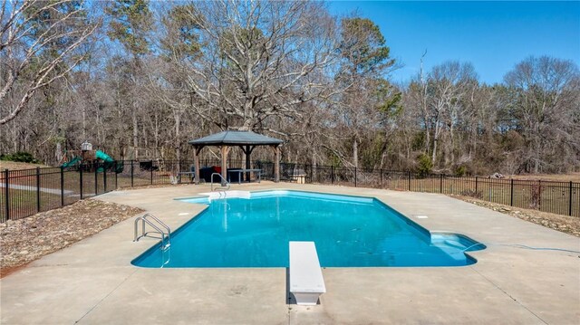 view of swimming pool with fence, a diving board, a fenced in pool, and a patio