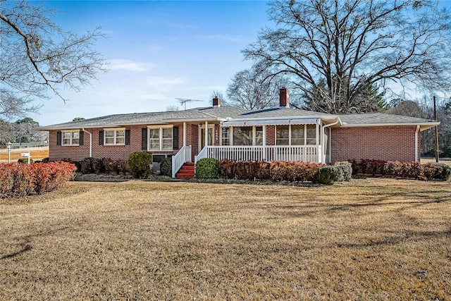 ranch-style house with a front yard, a chimney, and brick siding