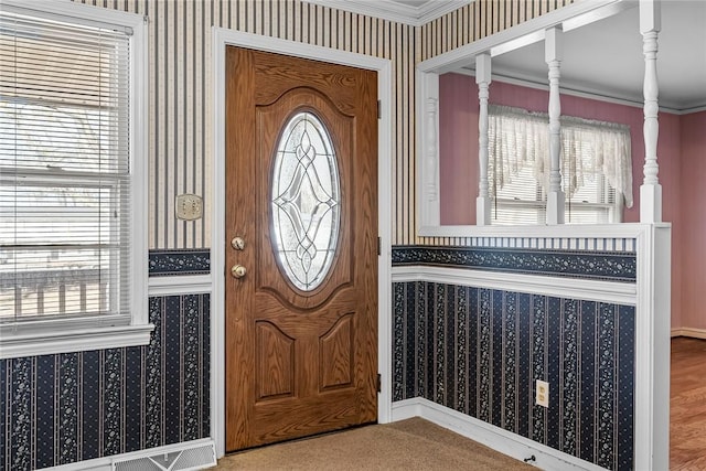 foyer entrance with ornamental molding and wallpapered walls