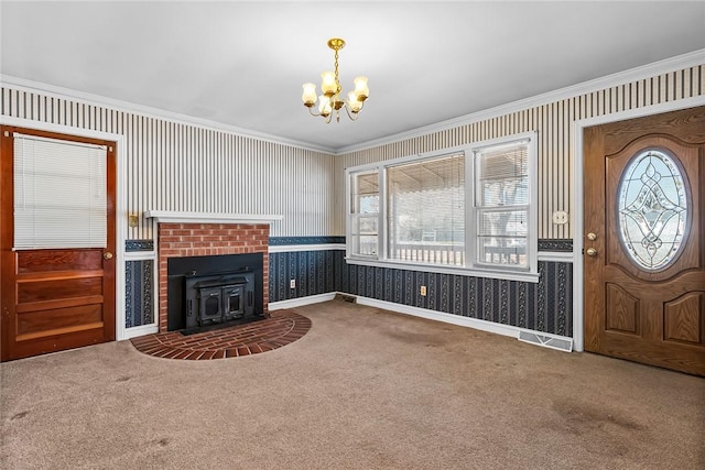 unfurnished living room with carpet floors, crown molding, an inviting chandelier, and wallpapered walls