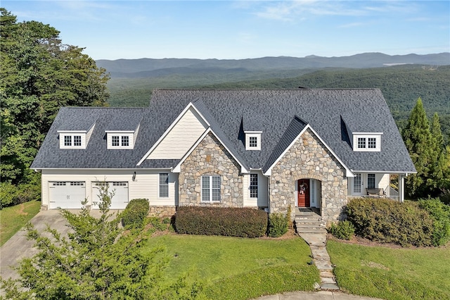 view of front of property with a shingled roof, a mountain view, a front lawn, and concrete driveway