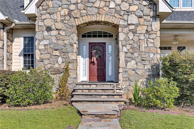 entrance to property featuring stone siding and a shingled roof