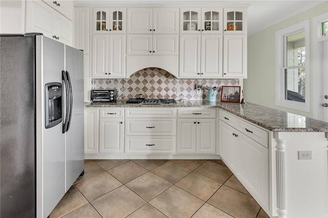 kitchen with a peninsula, white cabinetry, appliances with stainless steel finishes, tasteful backsplash, and glass insert cabinets