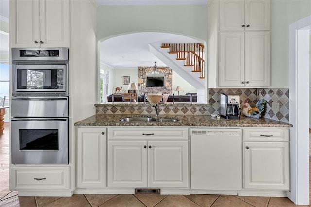 kitchen featuring dark stone countertops, dishwasher, a sink, and tasteful backsplash