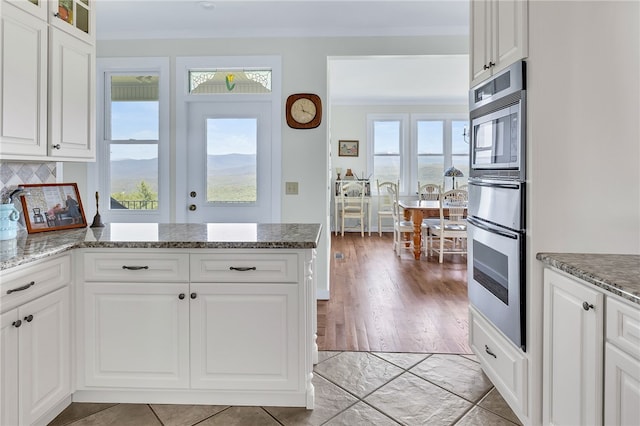 kitchen with tasteful backsplash, stone countertops, white cabinets, and glass insert cabinets