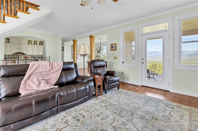 living area with ornamental molding, wood finished floors, and a healthy amount of sunlight