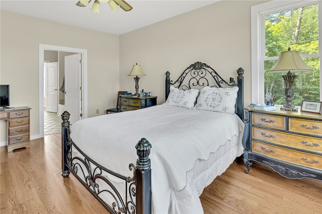 bedroom with connected bathroom, a ceiling fan, and wood finished floors