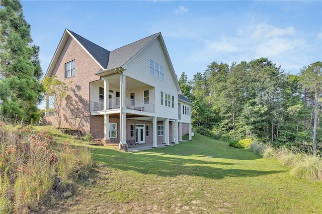 rear view of property featuring a patio area, brick siding, a yard, and a balcony