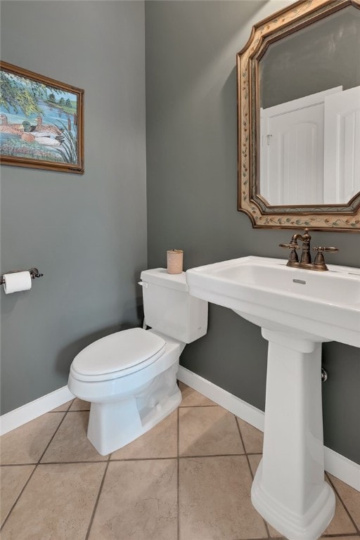 half bathroom with baseboards, toilet, and tile patterned floors