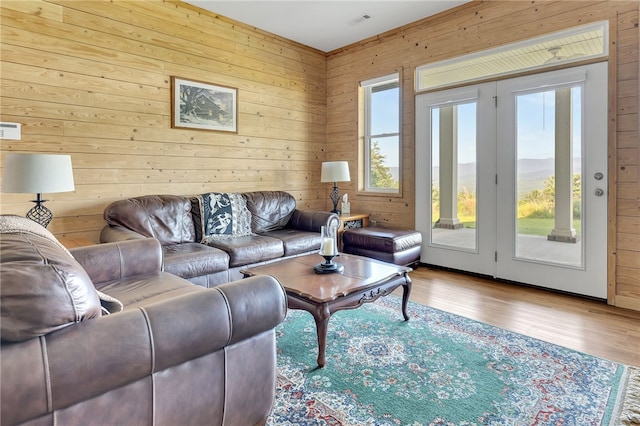 living area with visible vents, wooden walls, and wood finished floors