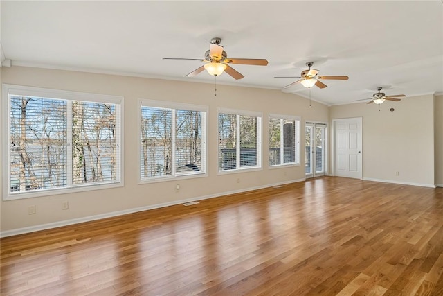 interior space with light wood finished floors, lofted ceiling, visible vents, ornamental molding, and baseboards